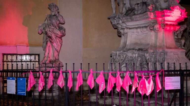 copyright: Lukas Fuchs Rote Tücher hängen an einem Zaun aus Stahl vor einer Kirche mit Statuen.
