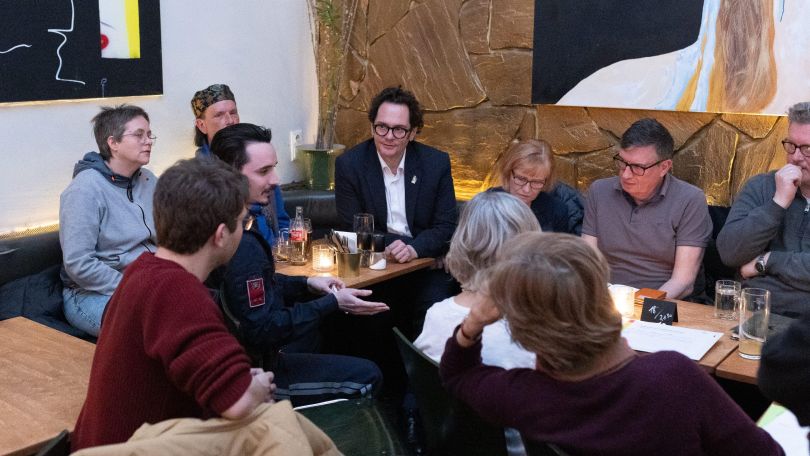 copyright: Lukas Fuchs 10 Personen sitzen um einen Tisch befinden sich in einem Gespräch.