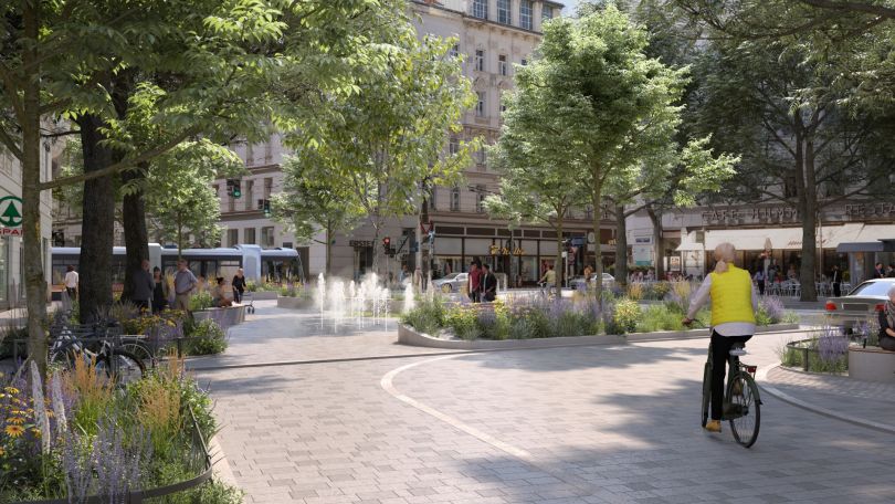 Eine Radfahrerin fährt zwischen Bäumen auf einem begrünten Platz zu