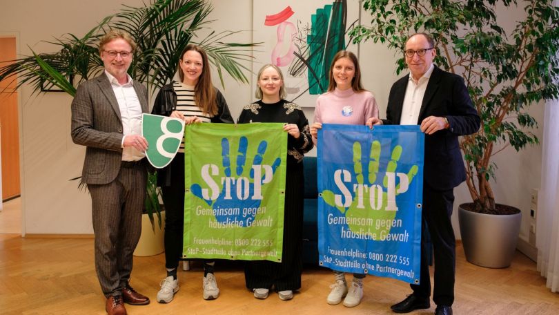 2 Herren in Anzug und 3 Frauen mit Banner "Stop - Gemeinsam gegen häusliche Gewalt"