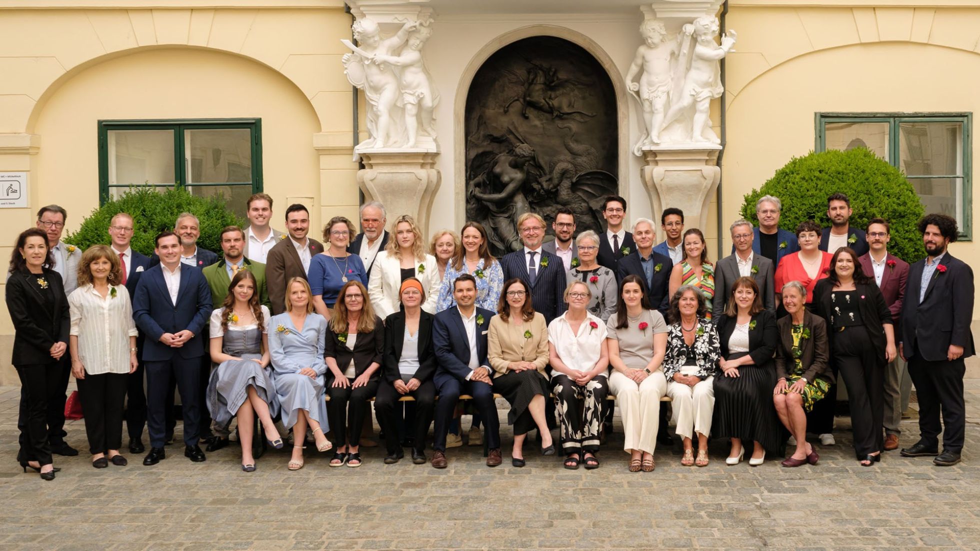 Gruppenfoto mit ungefähr 40 Personen im Freien vor einer Gebäudewand