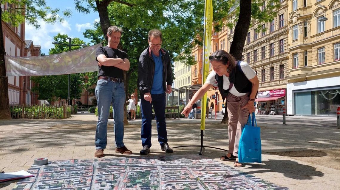 2 Männer und 1 Frau schauen auf einen überdimensionalen Stadtplan am Boden
