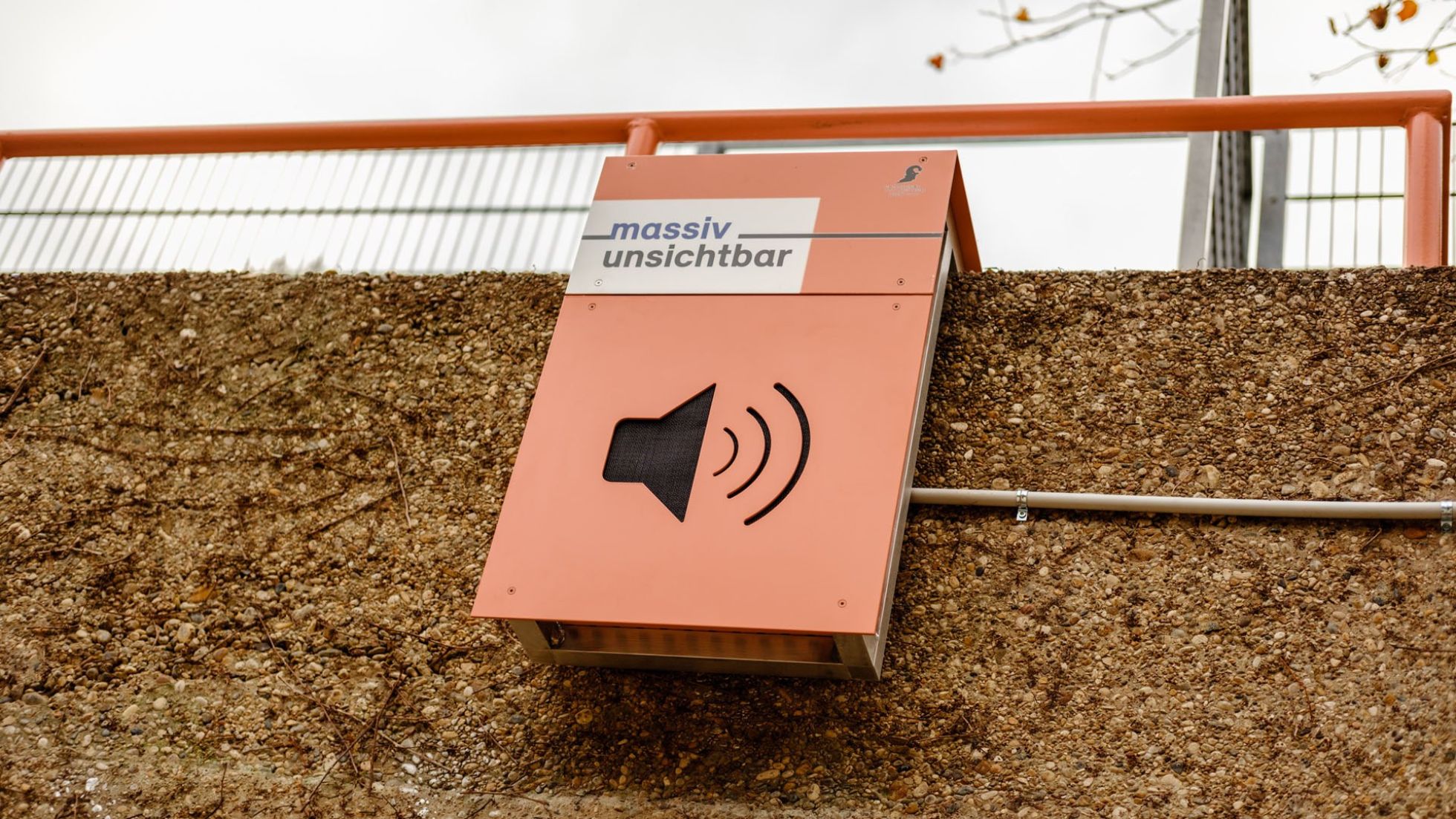 Ein quadratischer Lautsprecher in rosa mit der Aufschrift "massiv unsichtbar"