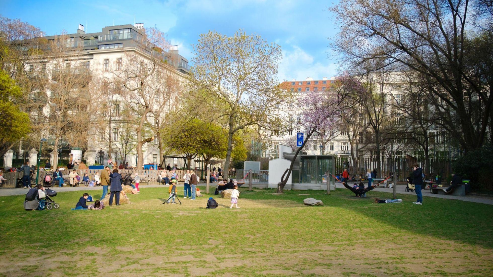 Park mit Bäumen und Besuchern auf einer Wiese