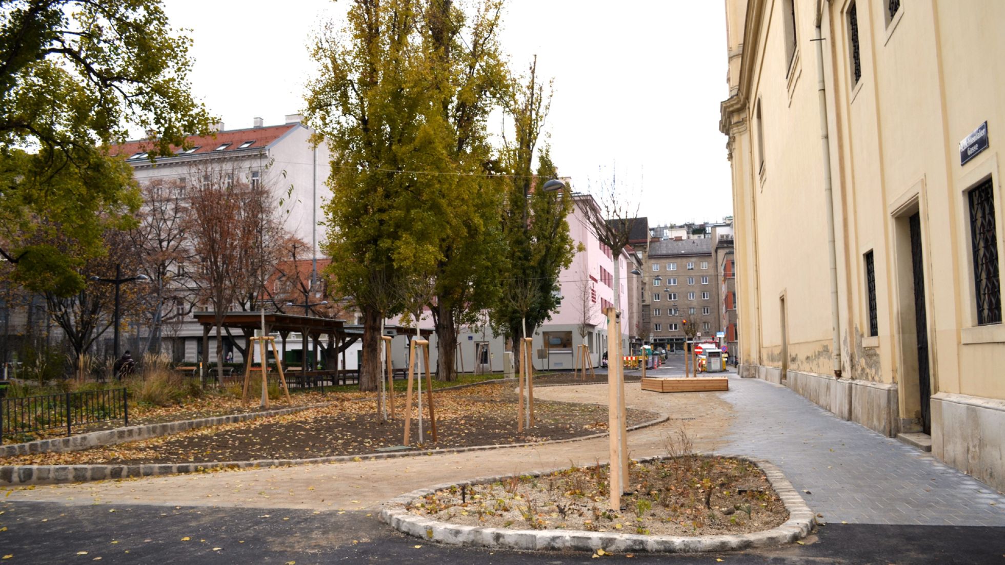 Neue Pflanzenbeete und Jungbäume vor einem Gebäude