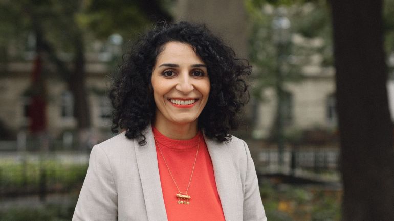 Bezirksvorsteherin Saya Ahmad im Freien vor Bäumen und Pflanzen