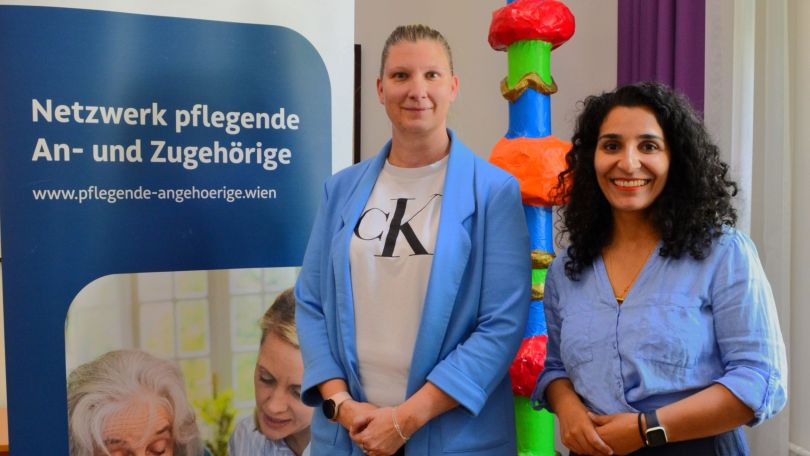 Eine Frau steht mit Bezirksvorsteherin Saya Ahmad vor einer Infotafel zum Pflegenetzwerk