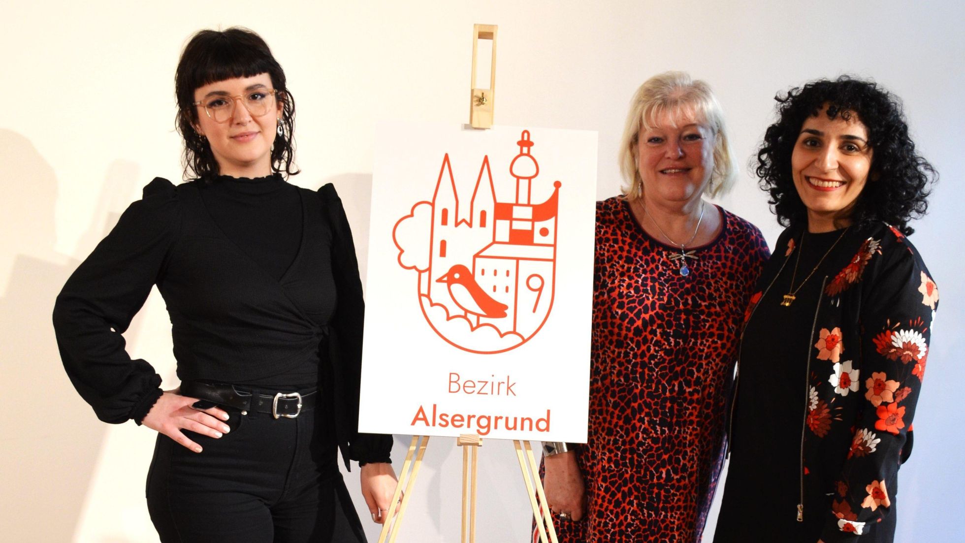 3 Frauen neben dem Bezirkslogo auf Leinwand