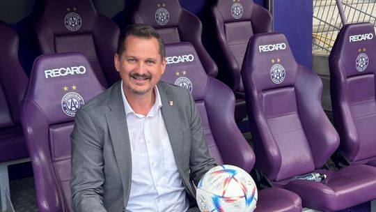 Bezirksvorsteher Marcus Franz mit einem Fußball auf einem violetten "Austria Wien"-Sessel