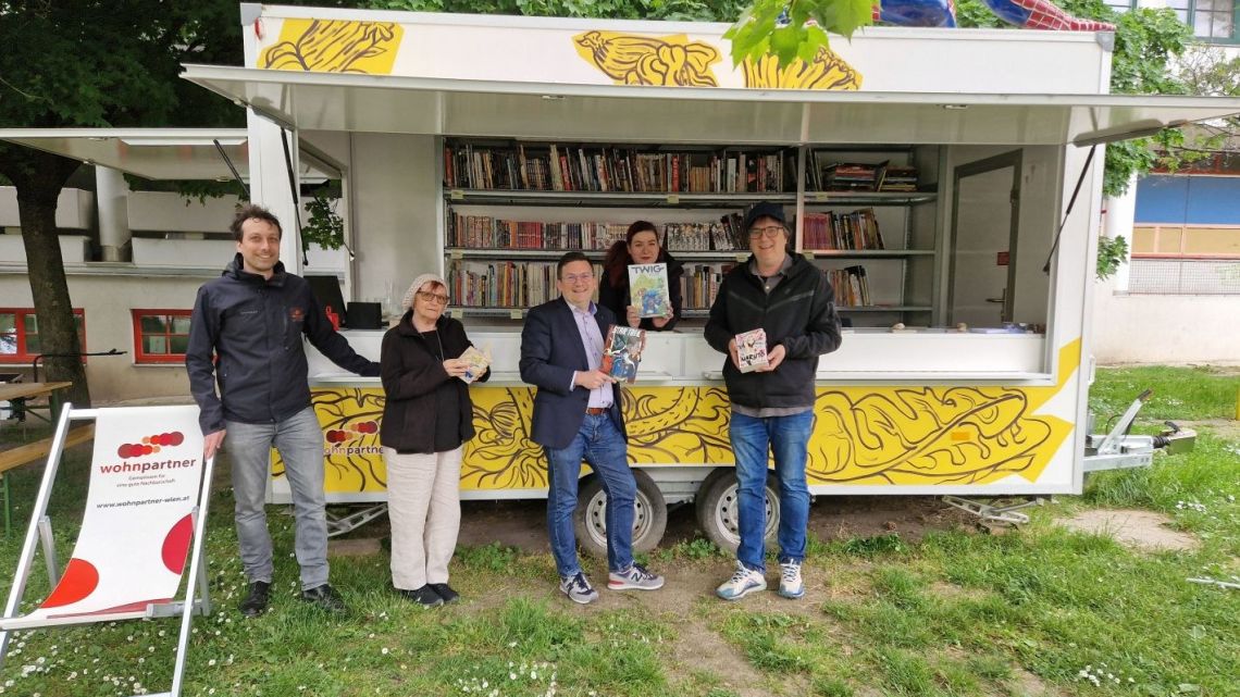4 Personen vor mobilem Shop mit Comic-Heften