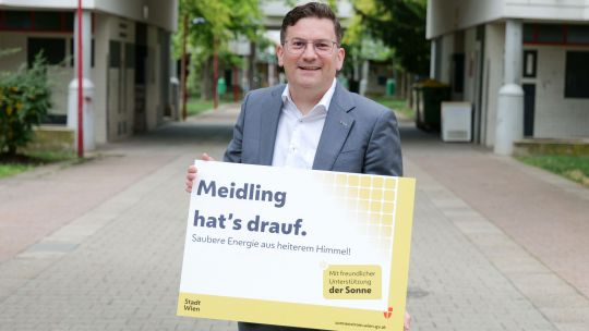 Bezirksvorsteher Wilfried Zankl hält ein Schild in der Hand mit der Aufschrift "Meidling hat's drauf. Saubere Energie aus heiterem Himmel!"