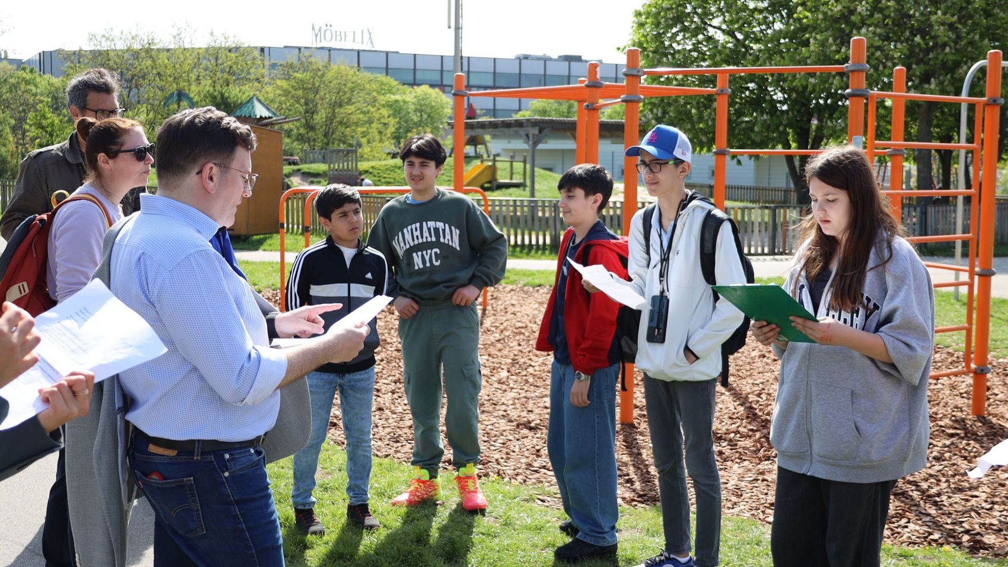 Bezirksvorsteher Wilfried Zankl im Gespräch mit mehreren Jugendlichen vor einem Klettergerüst im Park