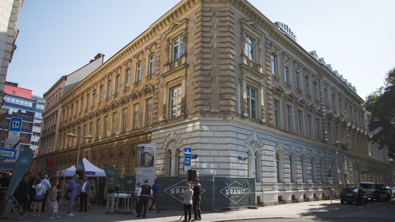 Amtshaus Meidling mit Polizei-Zelt davor, Banner einer Baufirma und einigen Menschen