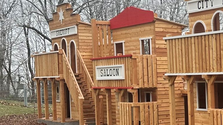 Holzspielgerät in Form einer Westernstadt auf einem Spielplatz