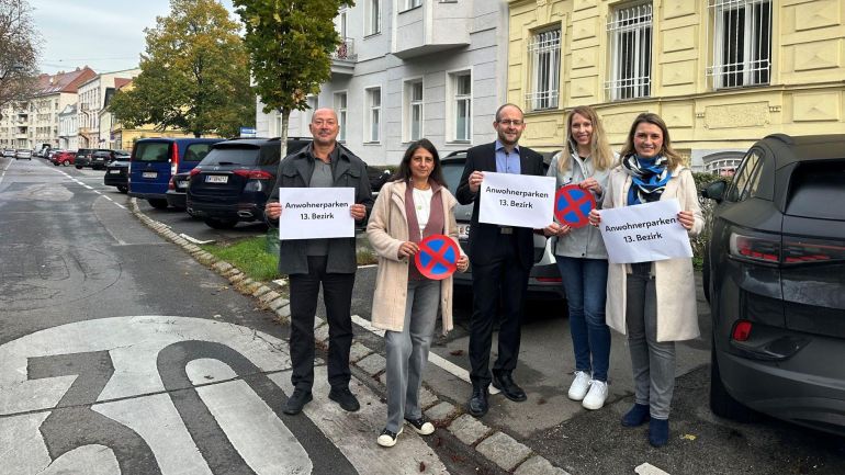 5 Bürger beziehungsweise Bürgerinnen stehen auf einer Straße und halten Schilder mit "Anwohnerparken 13. Bezirk" in die Kamera.