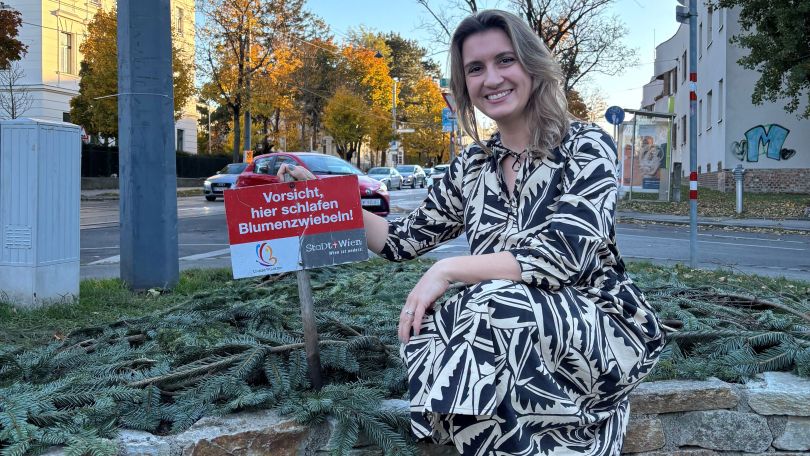 Johanna Zinkl sitzt am Rand eines erhöhten Blumenbeets, welches mit Zweigen abgedeckt ist.