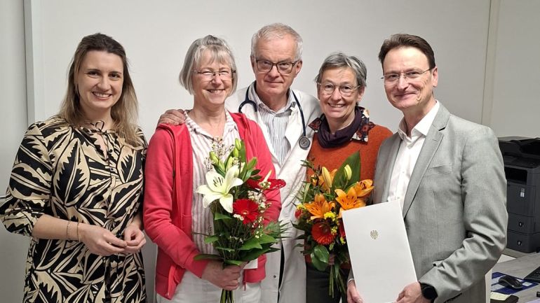 3 Frauen und 2 Männer blicken lachend in die Kamera. 2 der Frauen halten Blumensträuße in den Händen.