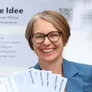 Bezirksvorsteherin Michaela steht vor einem Plakat mit der Aufschrift "Meine Idee".