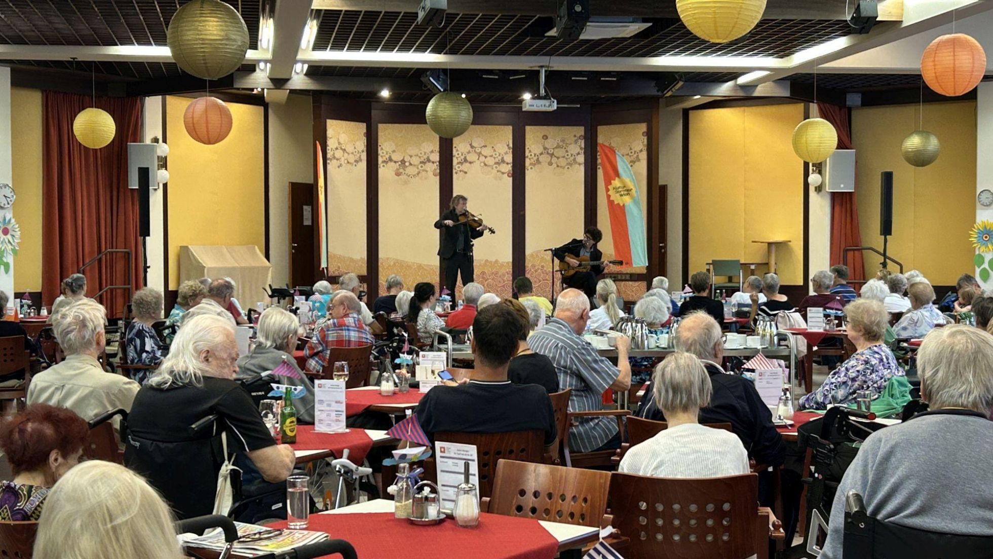 Gasthaus im Pensionistenwohnhaus mit einer Bühne auf der Musiker spielen