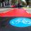 Breiter Radweg neben einer Straße. Auf der Fahrbahnfläche befinden sich eine großflächige rote Kennzeichnung und ein Piktogram von einem Fahrrad auf blauem Hintergrund.