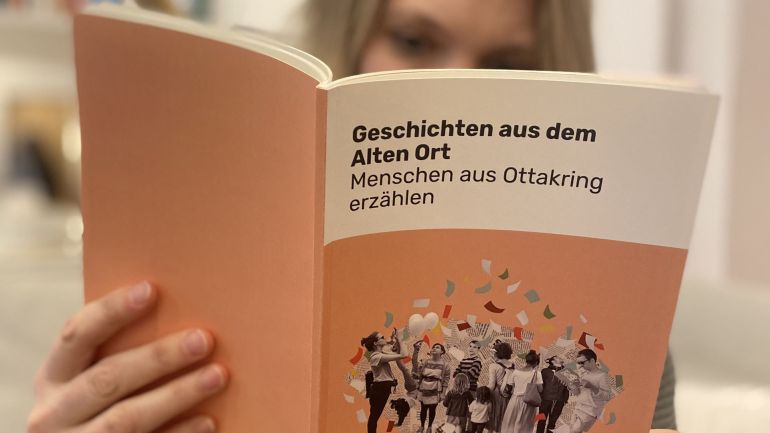 Jemand liest ein Buch mit dem Titel "Geschichten aus dem Alten Ort: Menschen aus Ottakring erzählen"