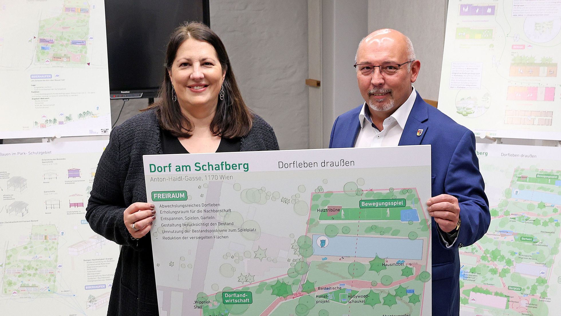 Kathrin Gaal und Peter Jagsch präsentieren einen Übersichtsplan zum Dorf am Schafberg