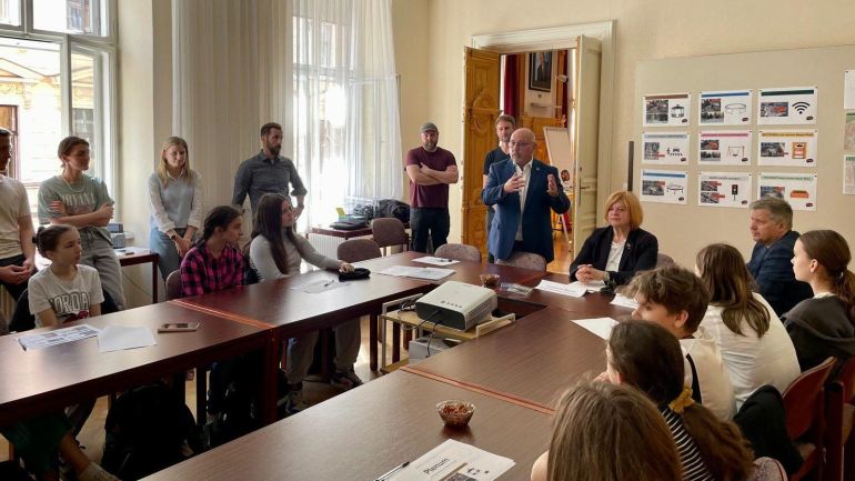 Jugendliche und Bezirksvorsteher sitzen bei Tischen und halten einen Workshop ab