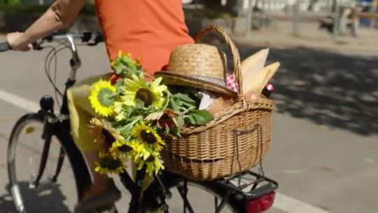 Standbild aus einem Video mit einer Radfahrerin mit Blumenkorb