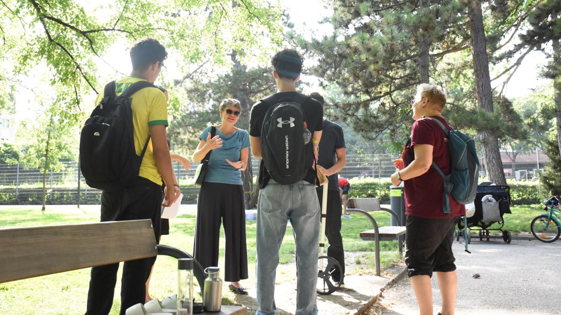 Eine Gruppe von Jugendlichen im Gespräch mit der Bezirksvorsteherin in einem Park