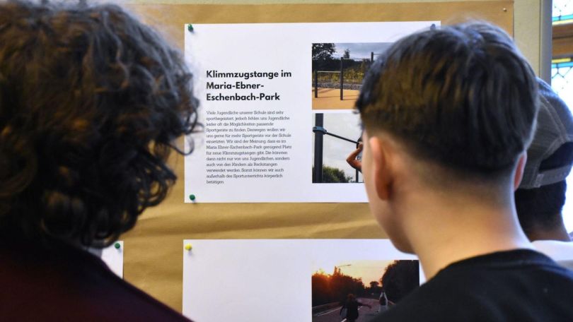 Schülerinnen betrachten gestellte Anträge auf einer Pinnwand.