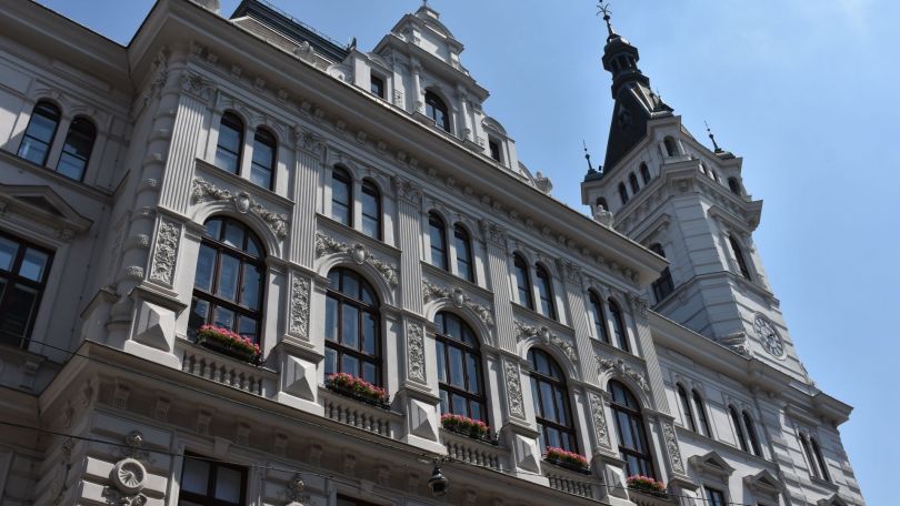 Altbau mit abgerundeten Holzfenstern mit Blumentkästen und einem Türmchen