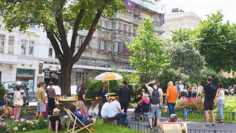 Menschen sitzen und stehen in einem Park und unterhalten sich