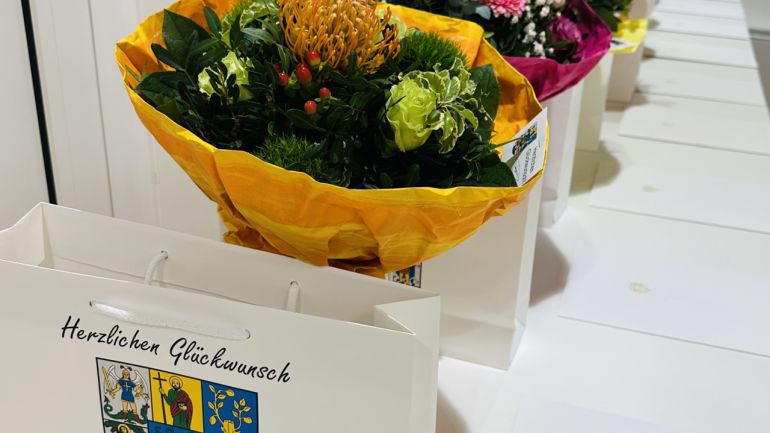 Blumenstrauß und Geschenkpaket mit Aufschrift "Herzlichen Glückwunsch"