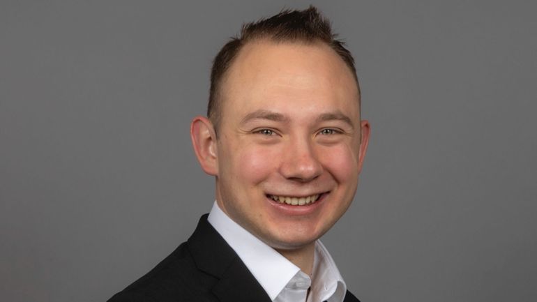 Ein junger Mann blickt lächelnd in die Kamera.