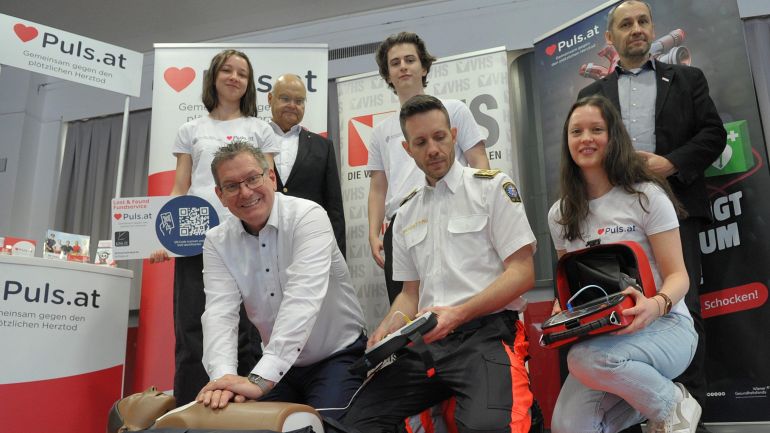 Mehrere Personen demonstrieren den Einsatz des Defibrillators und einer Herzdruckmassage an einer Erste-Hilfe-Übungspuppe.