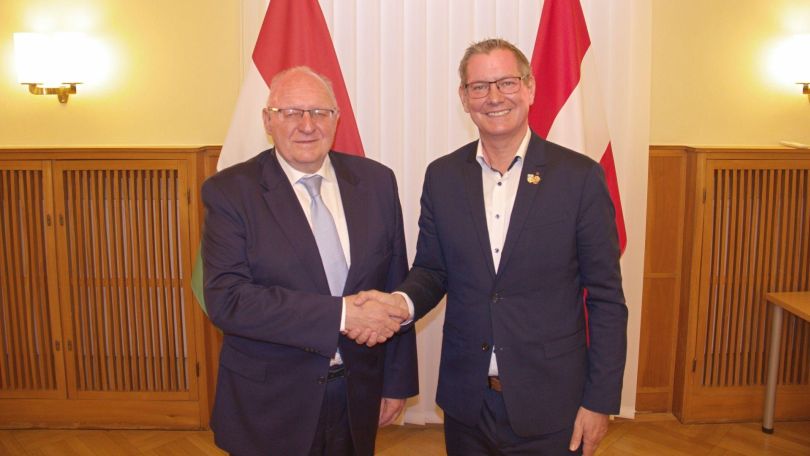 copyright: BV 21 2 Männer in Anzügen stehen vor 2 Flaggen und schütteln Hände.