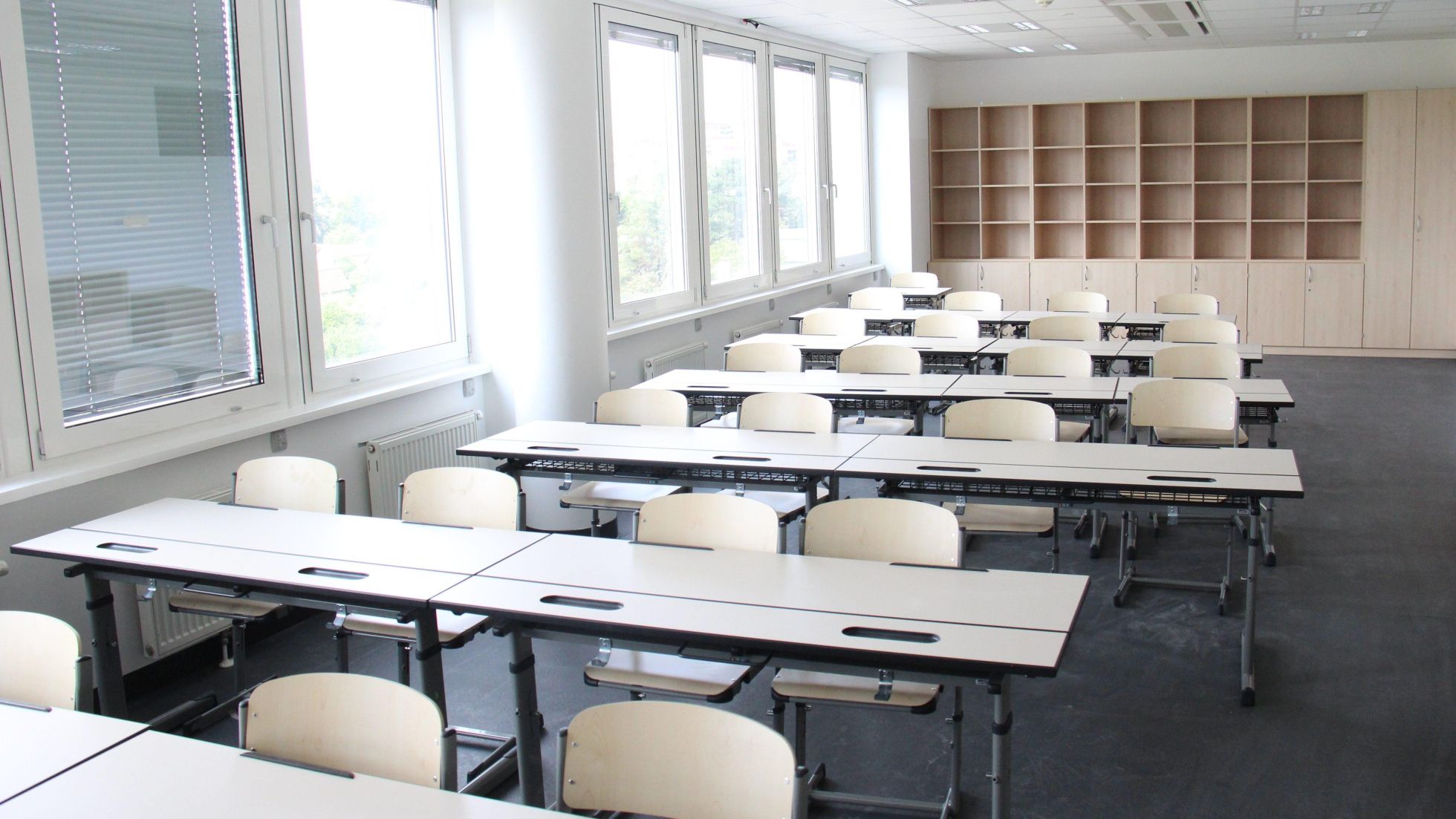 copyright: BV 21 Klassenzimmer mit mehreren Tischreihen in beige. Am Ende des Raumes steht ein großes Regal.