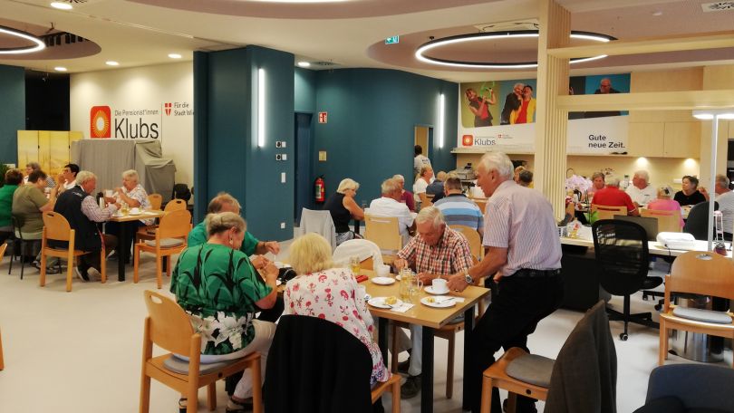 Eine Gruppe älterer Menschen an mehreren Tischen in einem Lokal