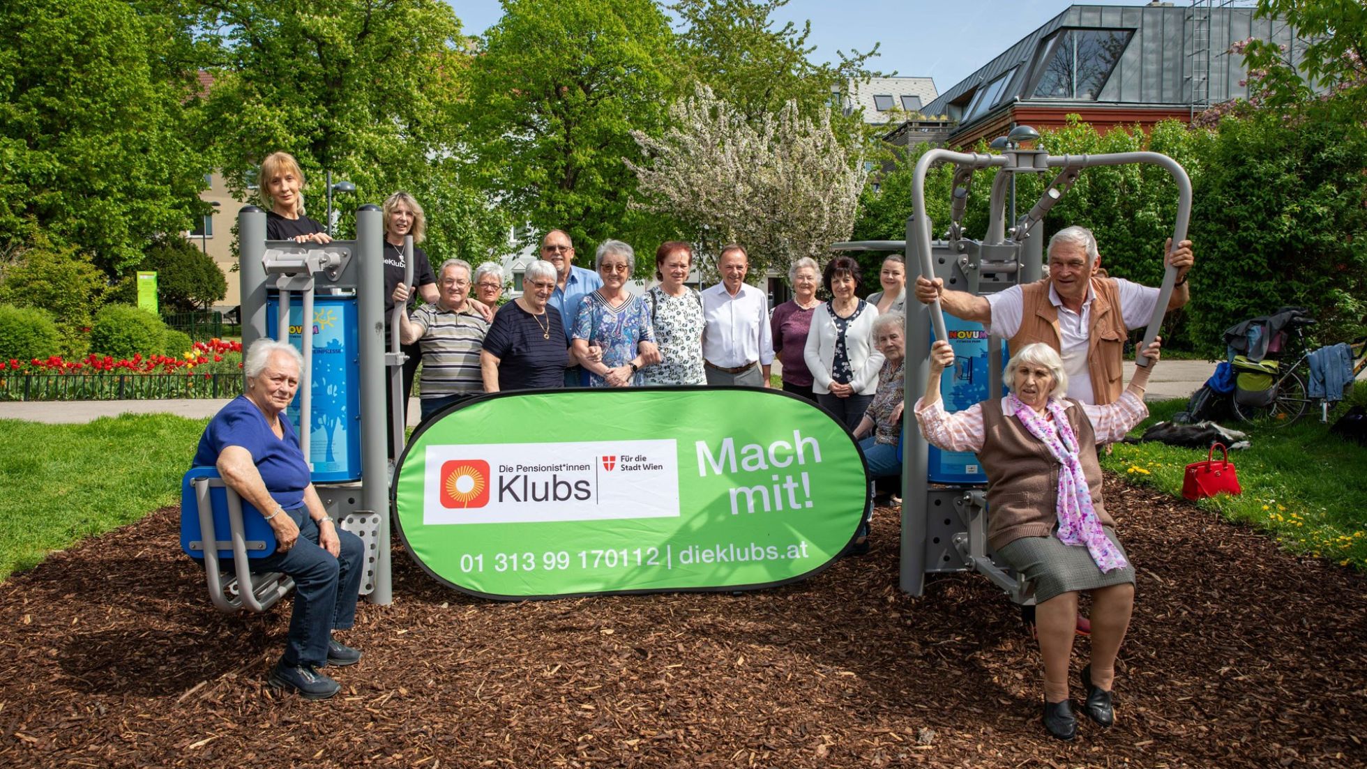 Gruppe an Senioren auf Fitnessgeräten, davor Banner "Mach mit!".