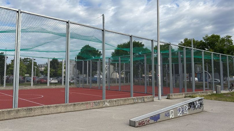 Sportplatz mit Zaun und modernem Bodenbelag; davor eine Skaterrampe