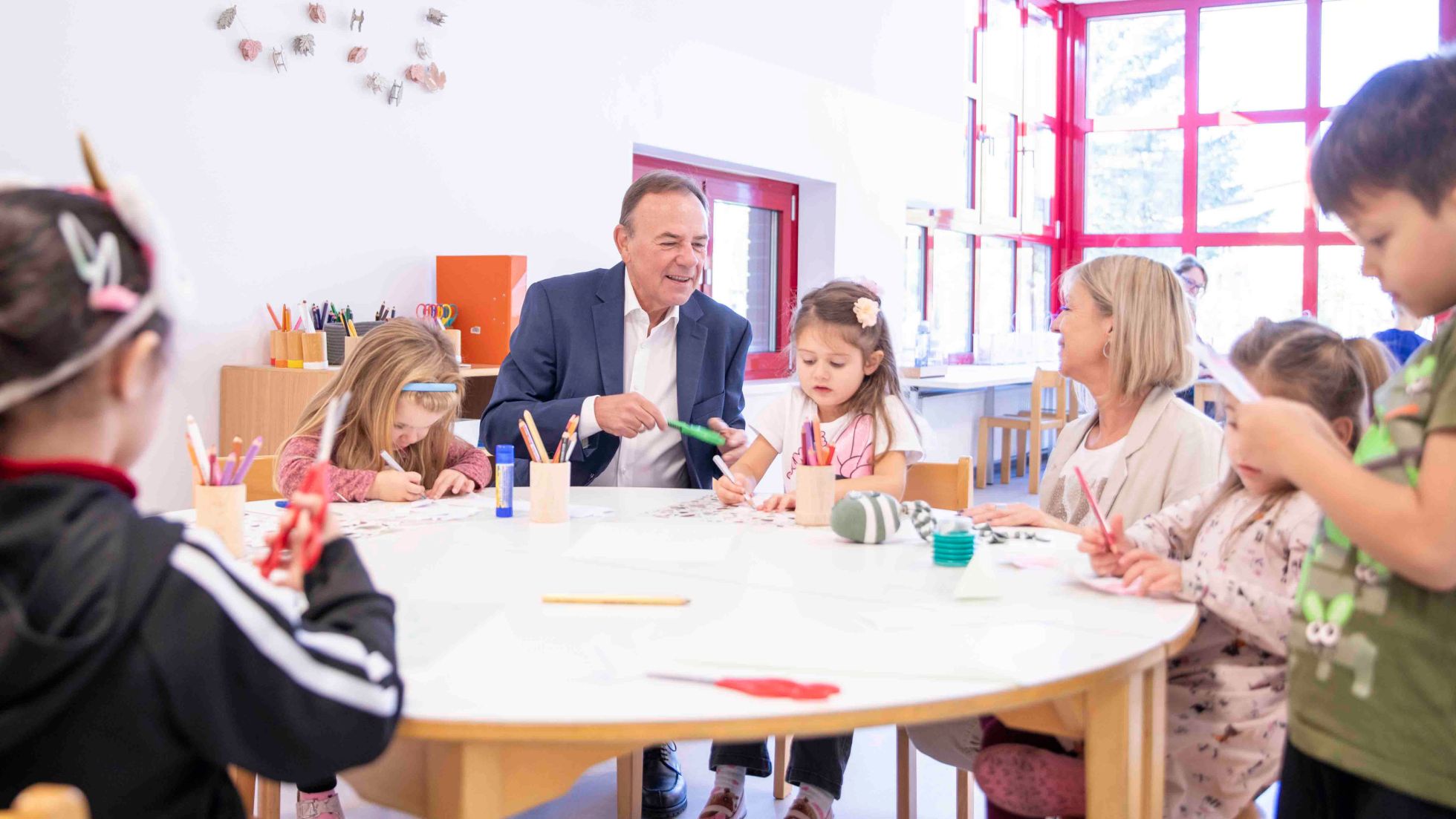 Bezirksvorsteher Gerald Bischof sitzt mit Kindern gemeinsam an einem Tisch