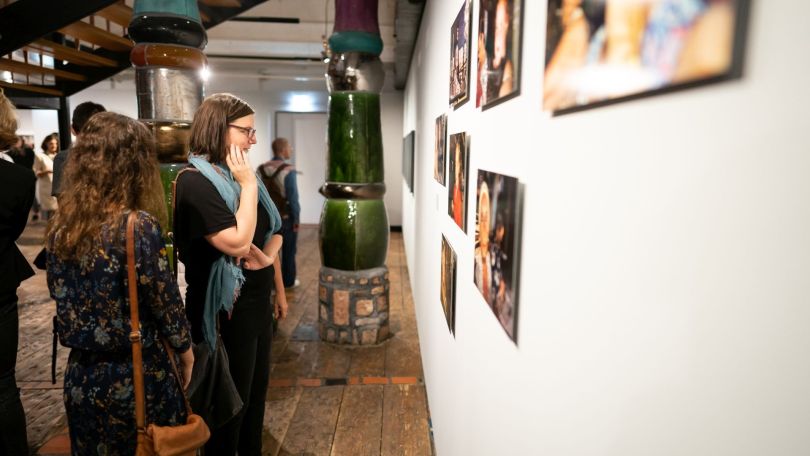 Besucherinnen schauen sich Bilder an den Wänden einer Ausstellung an.