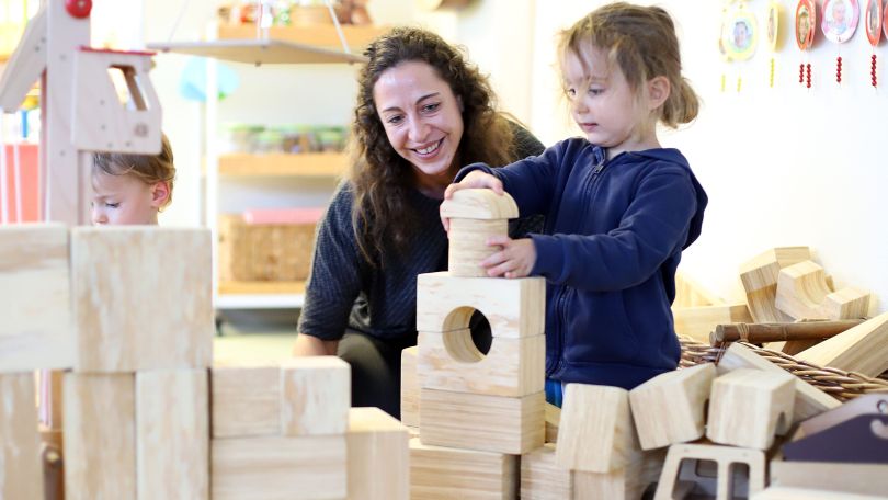 Frau baut mit Kind einen Holzturm.