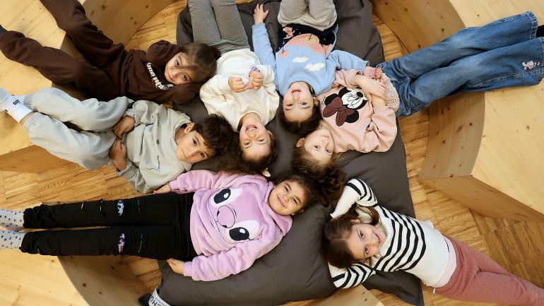 copyright: MA 10 - Wiener Kindergärten/Votava Martin Kinder liegen im Kreis auf einem großen Kissen