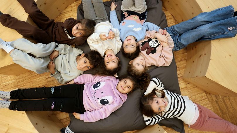 copyright: MA 10 - Wiener Kindergärten/Votava Martin Kinder liegen im Kreis auf einem großen Kissen