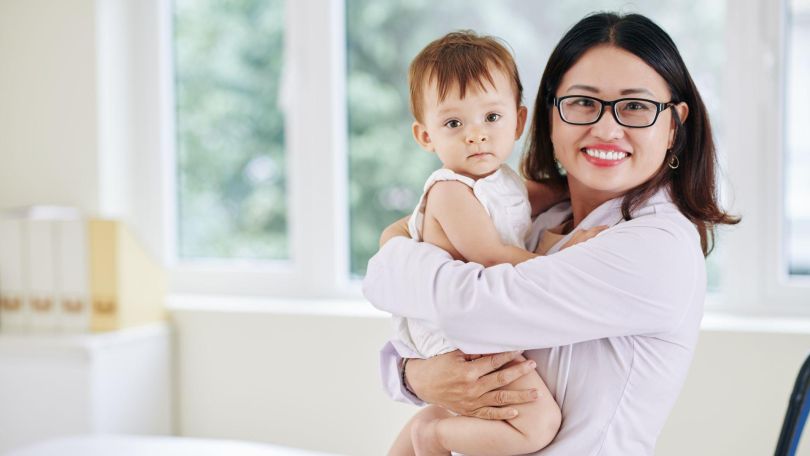 Mutter hält 2-jährigen Sohn auf dem Arm und lächelt