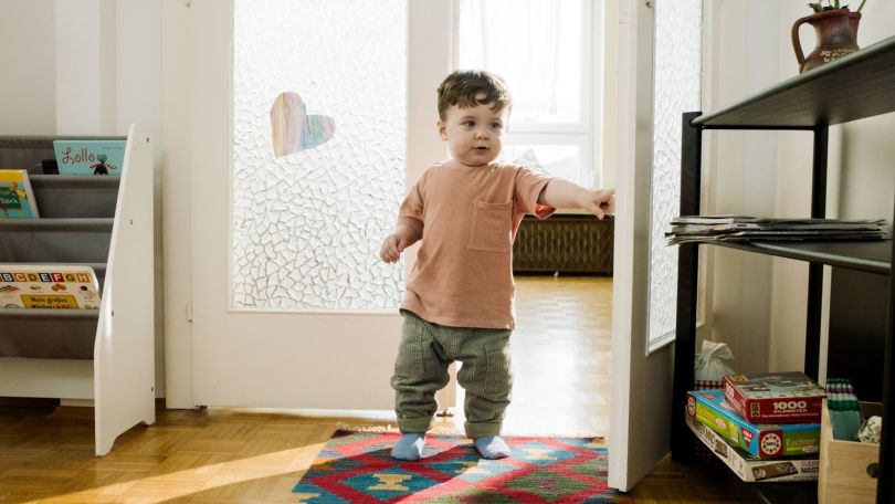 Kleiner Junge sitzt im Kinderzimmer auf Hocker