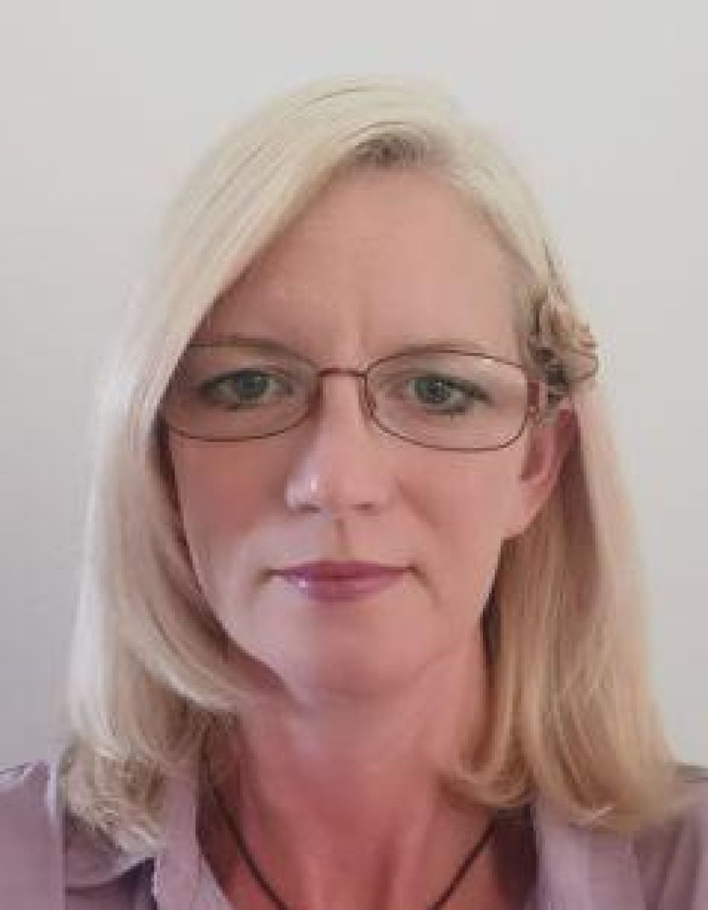 Frau mit langen blonden Haaren und Brille.