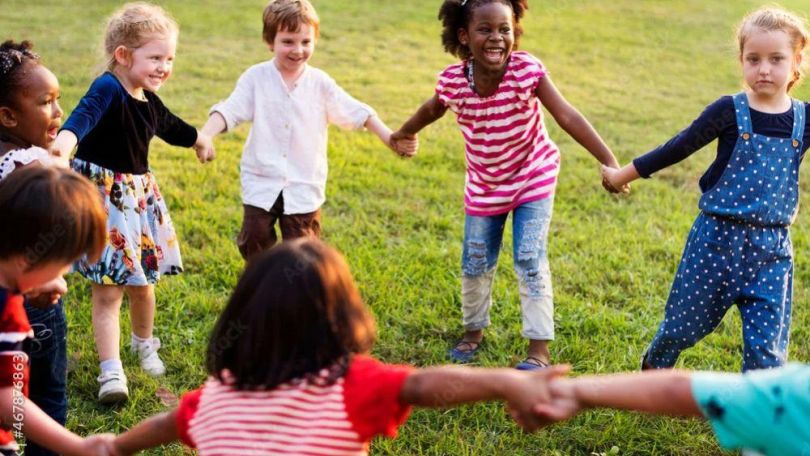 copyright: Rawpixel.com Kinder tanzen und lachen Hand in Hand auf einer Wiese.