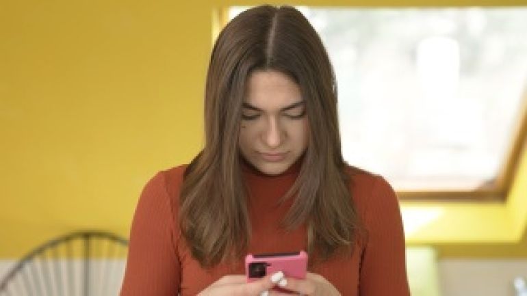 Eine junge Person schaut auf ihr Handy